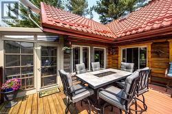 Spacious outdoor deck featuring natural wood planks, a sunroom with large windows, and a log cabin exterior - 