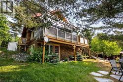 Multi-level log cabin exterior featuring a spacious upper deck with white railings, a ground-level patio with stepping stones, and a lower level entry with a red door - 
