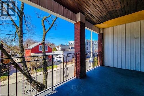 Spacious outdoor balcony featuring brick pillars, an ornate wrought iron railing, a wood-plank ceiling, and a painted floor - 254 Emerald Street N Unit# Upper, Hamilton, ON - Outdoor With Exterior