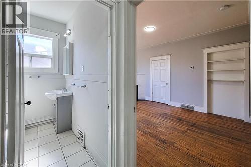 Bright bathroom featuring a pedestal sink, white tiled flooring, and a window for natural light - 254 Emerald Street N Unit# Upper, Hamilton, ON - Indoor Photo Showing Other Room