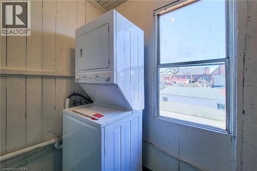 Dedicated laundry area featuring a stackable washer and dryer unit, wood paneling, and a double-hung window - 254 Emerald Street N Unit# Upper, Hamilton, ON - Indoor Photo Showing Laundry Room