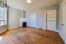 Spacious room featuring wood-finish flooring, a white-painted brick fireplace with a black grate, a built-in shelving unit, and a white trim package - 254 Emerald Street N Unit# Upper, Hamilton, ON  - Indoor With Fireplace 