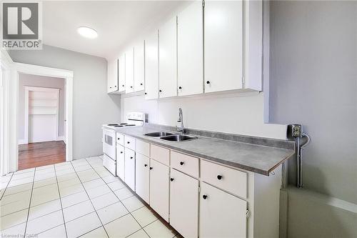 Kitchen featuring white cabinetry, a dual basin sink with chrome faucet, and a white electric range - 254 Emerald Street N Unit# Upper, Hamilton, ON - Indoor Photo Showing Kitchen With Double Sink