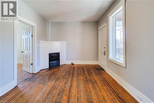 Hardwood flooring throughout featuring a white brick-surround fireplace - 254 Emerald Street N Unit# Upper, Hamilton, ON - Indoor Photo Showing Other Room