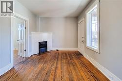 Hardwood flooring throughout featuring a white brick-surround fireplace - 