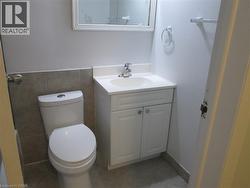 Bathroom featuring a white toilet, white vanity with integrated sink, chrome faucet, and a wall-mounted mirror - 