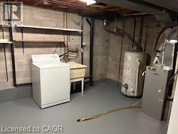 Utility area featuring a laundry sink, exposed structural elements, and concrete block walls - 