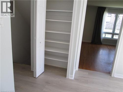 Built-in shelving unit with bi-fold doors, light wood-finish flooring, and white baseboards - 648 Francis Road, Burlington, ON - Indoor Photo Showing Other Room