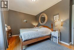 Bedroom featuring wood-finish flooring, neutral gray wall tones, and white baseboards - 