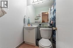 Bathroom featuring a white vanity with integrated sink, a wall-mounted mirror, and a toilet with an adjacent shower area - 