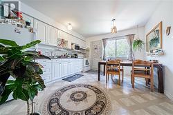 Kitchen and dining area featuring white cabinetry, light-toned flooring, an overhead flush-mount light fixture, and a pendant light fixture - 
