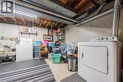 Laundry area featuring a large white washing machine, dryer, and utility sink - 