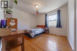 Room featuring wood-finish flooring, a double window with blinds, white walls, and a ceiling-mounted light fixture - 