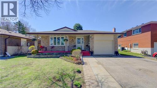Brick exterior featuring a covered front porch, an attached single-car garage, a paved driveway, and a front lawn with established garden beds - 170 Martinglen Crescent, Kitchener, ON - Outdoor