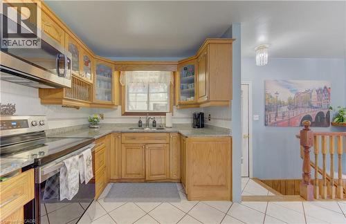 Kitchen featuring wood cabinetry, stainless steel appliances, a tile backsplash, and light-toned countertops - 170 Martinglen Crescent, Kitchener, ON - Indoor Photo Showing Kitchen