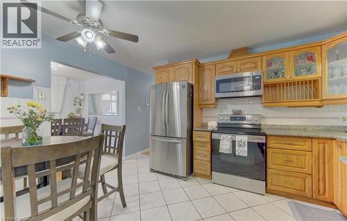 Kitchen featuring wood cabinetry, stainless steel appliances, and white tile flooring - 170 Martinglen Crescent, Kitchener, ON - Indoor Photo Showing Kitchen