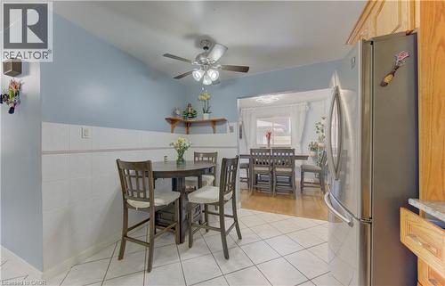 Kitchen area featuring white square floor tiles, a stainless-steel refrigerator, wood-finish cabinetry, and a ceiling fan with integrated lighting - 170 Martinglen Crescent, Kitchener, ON - Indoor Photo Showing Dining Room
