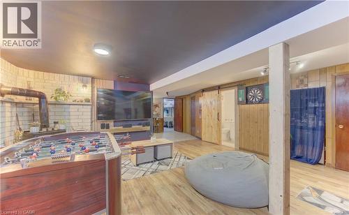Recreation room featuring wood-finish flooring and a white brick-style wall - 170 Martinglen Crescent, Kitchener, ON - Indoor