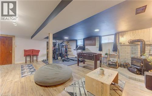 Finished lower level featuring light wood-finish flooring, recessed lighting, exposed ceiling beams, a wood-burning stove with a brick surround, and a built-in wood cabinet - 170 Martinglen Crescent, Kitchener, ON - Indoor With Fireplace