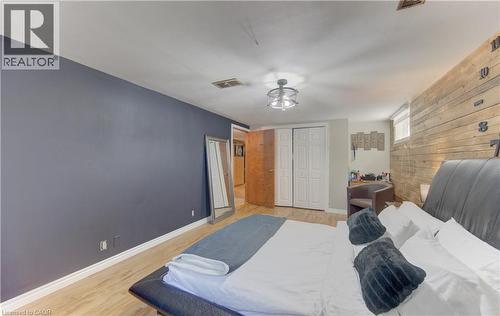 Bedroom featuring a wood-finish accent wall, ceiling-mounted light fixture, wood-finish flooring, and bi-fold closet doors - 170 Martinglen Crescent, Kitchener, ON - Indoor Photo Showing Bedroom