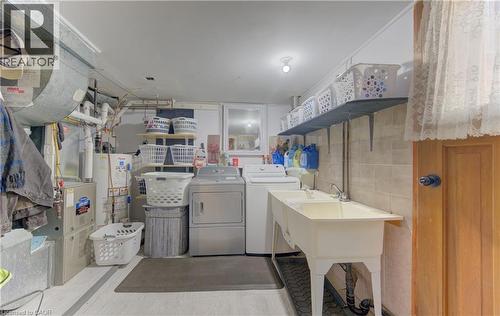 Dedicated utility area with a double basin sink, expansive wall shelving, and durable tile wainscoting - 170 Martinglen Crescent, Kitchener, ON - Indoor Photo Showing Laundry Room