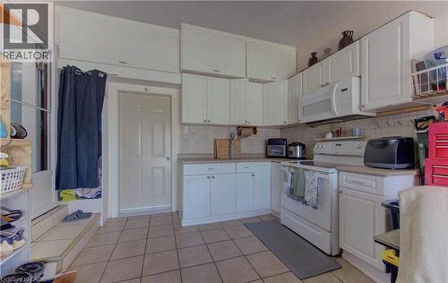Kitchen featuring extensive white cabinetry, a built-in microwave, tiled flooring, and a neutral backsplash - 170 Martinglen Crescent, Kitchener, ON - Indoor Photo Showing Kitchen