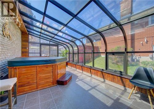 Solarium featuring a built-in hot tub with wood paneling, extensive glass enclosure, brick accent wall, and tiled flooring - 170 Martinglen Crescent, Kitchener, ON -  Photo Showing Other Room