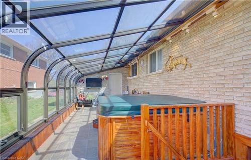 Solarium featuring a glass roof, full-height windows, a built-in hot tub with wood-finish surround, light-colored brick wall, and track lighting - 170 Martinglen Crescent, Kitchener, ON -  With Exterior