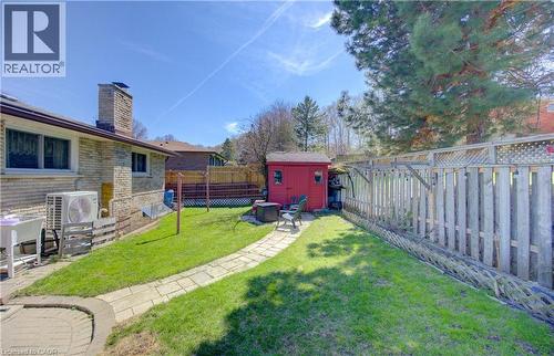 Expansive backyard featuring a manicured lawn, a stone paver pathway, a red storage shed, and a wooden privacy fence - 170 Martinglen Crescent, Kitchener, ON - Outdoor