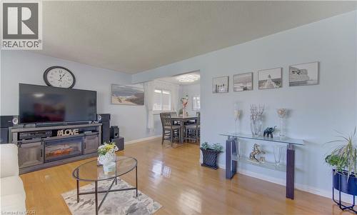 Living room featuring wood-finish flooring, light blue wall paint, and a built-in media console with an electric fireplace - 170 Martinglen Crescent, Kitchener, ON - Indoor Photo Showing Living Room