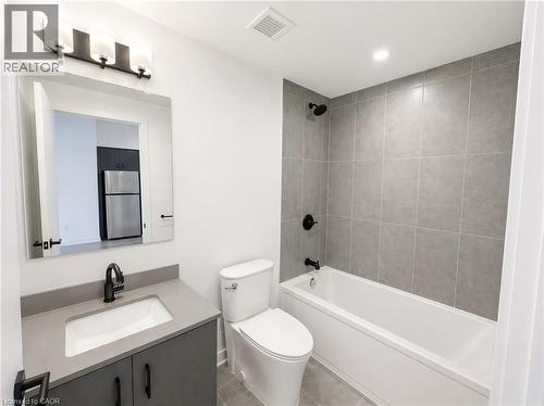 Contemporary bathroom featuring a white bathtub with subway tile surround, a vanity with a rectangular undermount sink, a gray countertop, and matte black fixtures - 4878 Powers Common Unit# 1108, Burlington, ON - Indoor Photo Showing Bathroom
