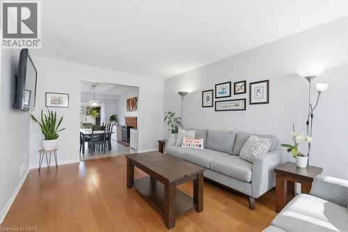 Hardwood flooring extends throughout this living space, featuring light gray walls and an open doorway leading to a dining area with a fireplace - 44 Lorilee Crescent, Kitchener, ON - Indoor Photo Showing Living Room