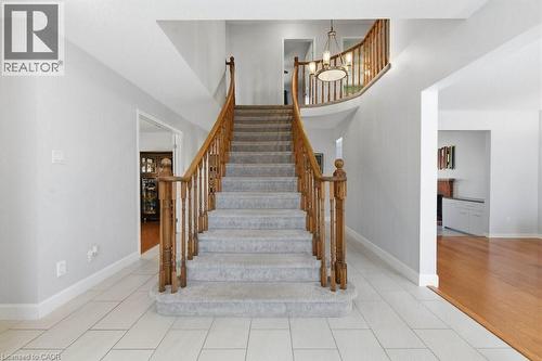 Foyer featuring a grand staircase with wood banisters and carpeted treads, tile flooring, and a second-story landing with a chandelier - 44 Lorilee Crescent, Kitchener, ON - Indoor Photo Showing Other Room
