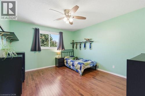 Room featuring wood-finish flooring, a ceiling fan with integrated lighting, and a single window with dark drapery - 44 Lorilee Crescent, Kitchener, ON - Indoor Photo Showing Bedroom