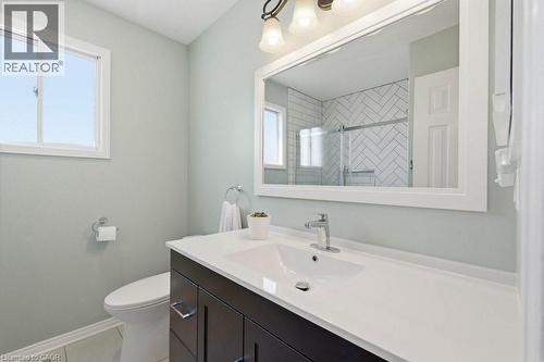 Bathroom featuring a dark wood-finish vanity with a white countertop and integrated sink, a large framed mirror, and a window with white trim - 44 Lorilee Crescent, Kitchener, ON - Indoor Photo Showing Bathroom