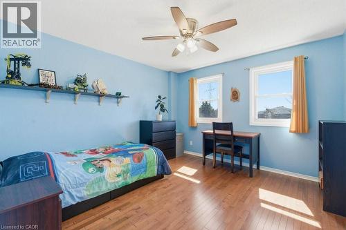 Bright room with wood-finish flooring, two large windows, a ceiling fan with integrated lighting, and a built-in wall shelf - 44 Lorilee Crescent, Kitchener, ON - Indoor Photo Showing Bedroom