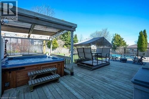 Spacious wood deck featuring a covered hot tub, an open-air swimming pool, and a black wrought-iron fence - 44 Lorilee Crescent, Kitchener, ON - Outdoor