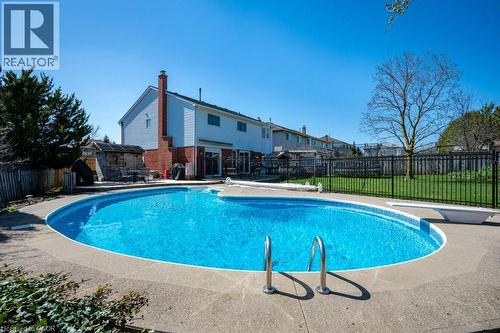 Oval-shaped inground pool with concrete surround and metal access ladders - 44 Lorilee Crescent, Kitchener, ON - Outdoor With In Ground Pool With Backyard