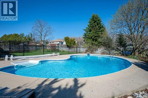 Kidney-shaped inground pool featuring a textured concrete surround - 44 Lorilee Crescent, Kitchener, ON - Outdoor With In Ground Pool With Backyard