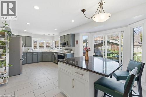 Modern kitchen featuring gray cabinetry, stainless steel appliances, a center island with a dark countertop, white subway tile backsplash, and light-colored tile flooring - 44 Lorilee Crescent, Kitchener, ON - Indoor