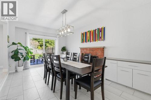 Spacious dining area featuring a brick fireplace with a stone mantel, a built-in white cabinet system with a contrasting countertop, and contemporary pendant lighting - 44 Lorilee Crescent, Kitchener, ON - Indoor Photo Showing Dining Room