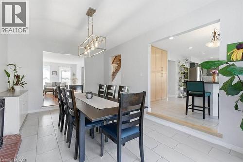 Spacious dining area featuring neutral tile flooring, a modern linear chandelier, and an open entryway to the living room - 44 Lorilee Crescent, Kitchener, ON - Indoor Photo Showing Dining Room