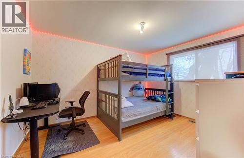 Hardwood-style flooring throughout this room, featuring textured wallpaper, a single window with a roller shade, and a flush-mount ceiling light fixture - 98 Shea Crescent, Kitchener, ON - Indoor Photo Showing Bedroom