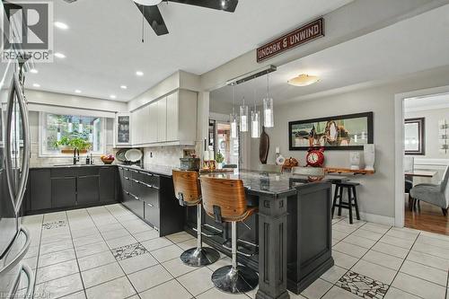 Modern kitchen featuring a central island with pendant lighting, white upper cabinetry, dark lower cabinetry, and a patterned tile floor - 2324 Homer Drive, Burlington, ON - Indoor