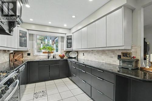 U-shaped kitchen featuring two-tone cabinetry, dark countertops, and a full tile backsplash - 2324 Homer Drive, Burlington, ON - Indoor Photo Showing Kitchen With Upgraded Kitchen