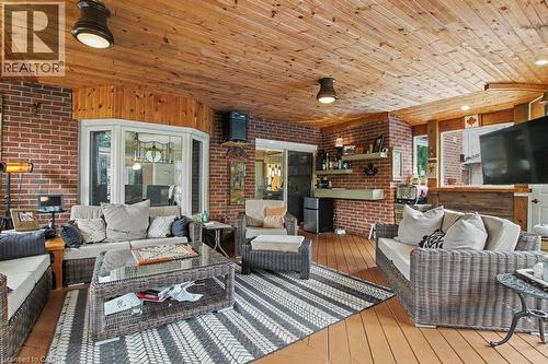 Expansive enclosed patio featuring a wood-finish ceiling, brick walls, bay window with stained glass detail, and wood-finish flooring - 2324 Homer Drive, Burlington, ON - Outdoor With Deck Patio Veranda With Exterior