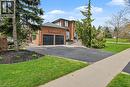 Traditional brick residence featuring a two-car garage, asphalt driveway, mature front landscaping, stone-clad entrance steps, and a sidewalk - 2324 Homer Drive, Burlington, ON  - Outdoor 