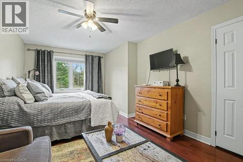 Bedroom featuring a window with exterior tree scenery, wood-finish flooring, a ceiling fan, and a paneled door - 2324 Homer Drive, Burlington, ON - Indoor Photo Showing Bedroom