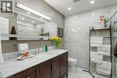 Bathroom featuring a dark wood-finish vanity with a white stone countertop, undermount sink, and chrome faucet - 2324 Homer Drive, Burlington, ON - Indoor Photo Showing Bathroom