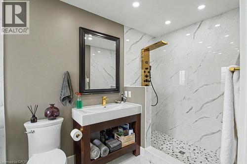 Contemporary bathroom featuring a dark wood-finish vanity with an integrated basin, a gold-tone faucet, and a framed mirror - 2324 Homer Drive, Burlington, ON - Indoor Photo Showing Bathroom